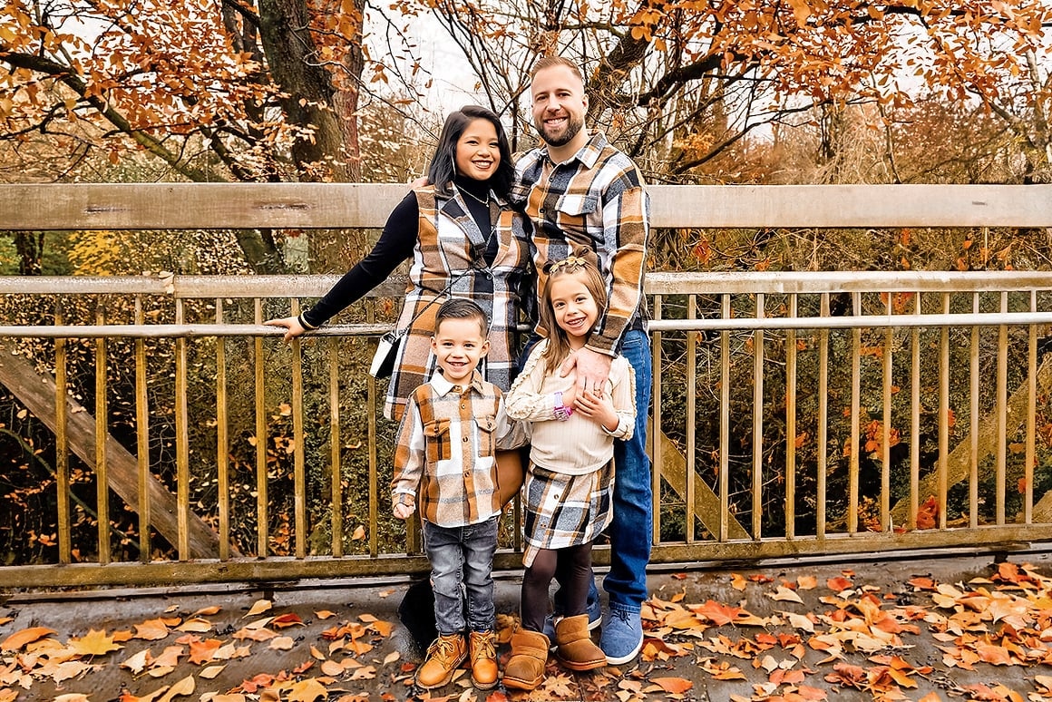 Family of four in matching plaid on a bridge during an autumn photo session